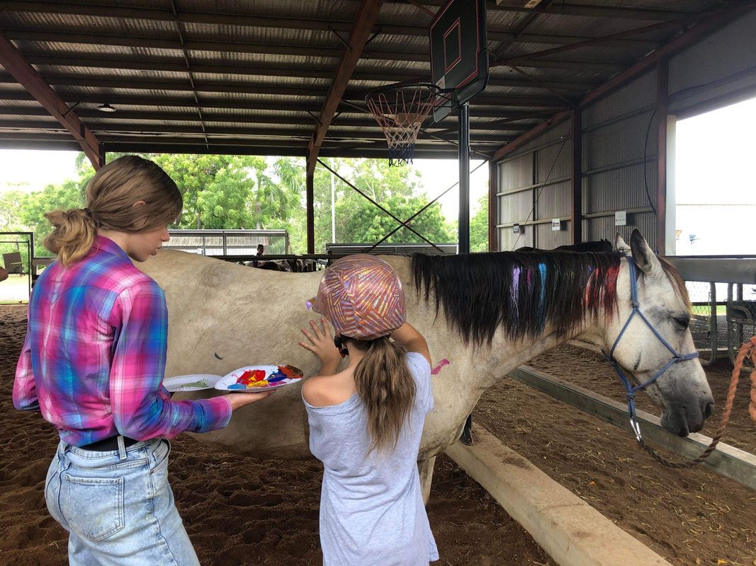 Two girls are standing next to a horse in a barn.