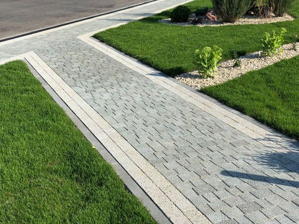 A brick walkway leading to a lush green lawn.