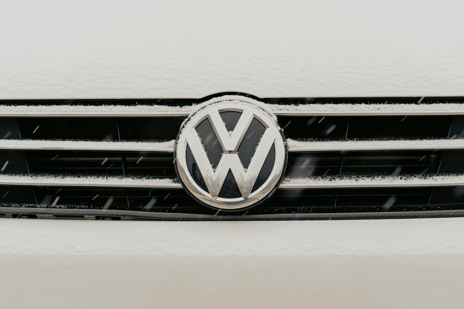 Volkswagen logo on a black car grille against a white body panel