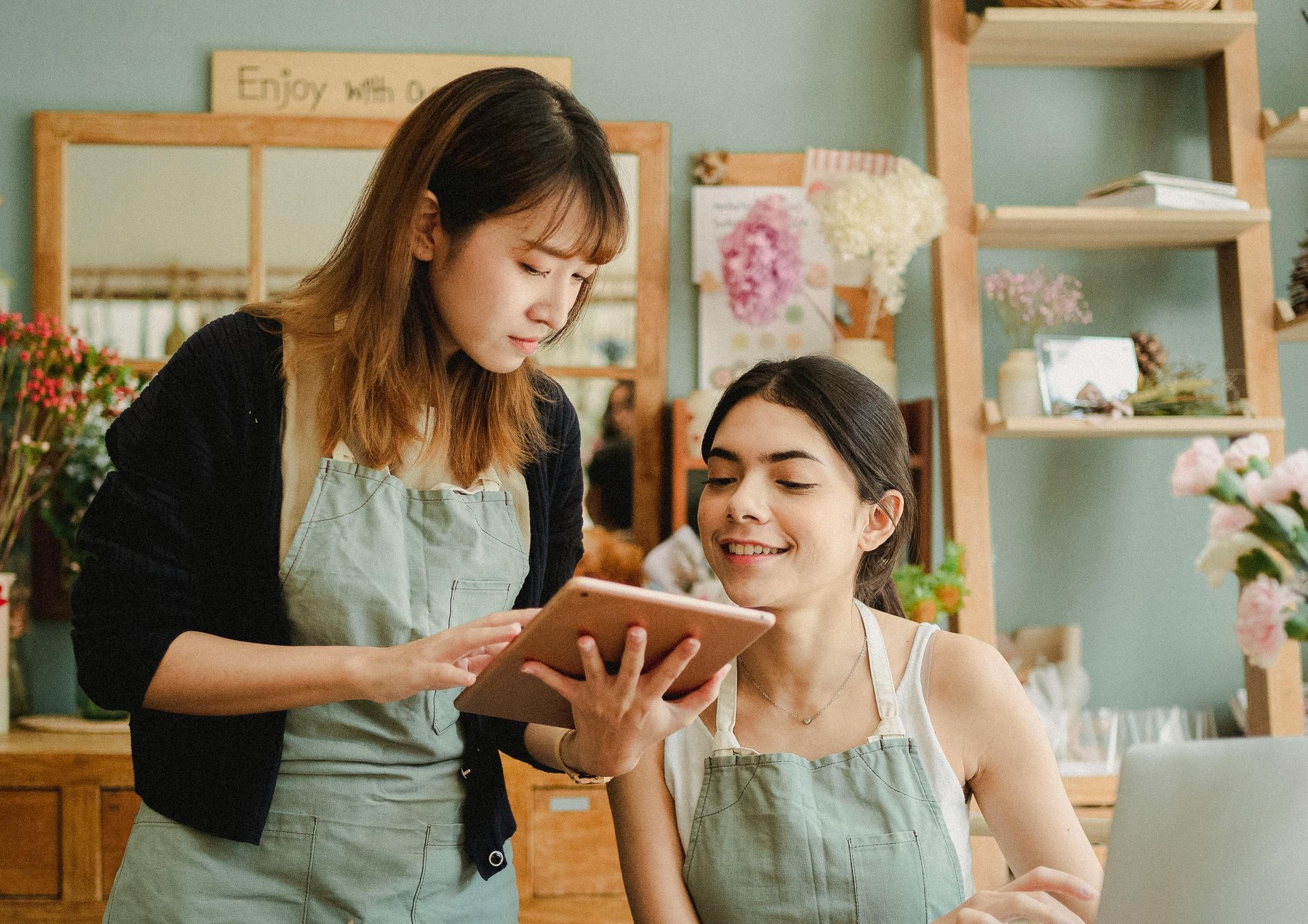 Duas mulheres olhando para um tablet em uma floricultura.
