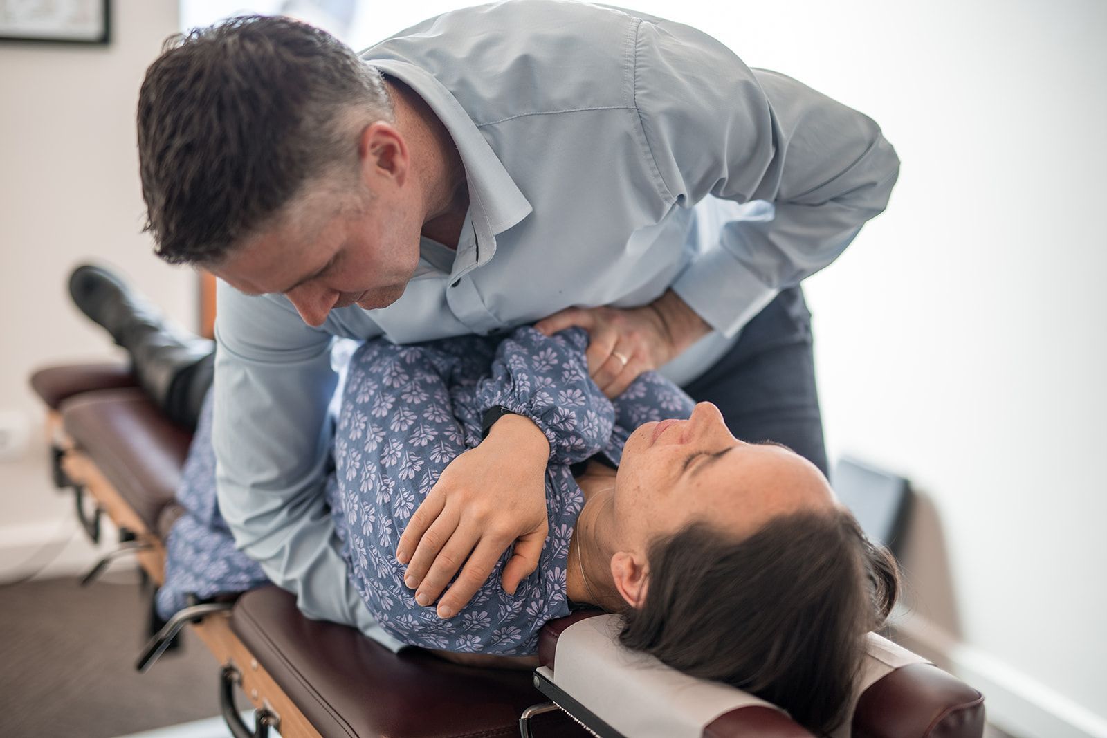 A man is adjusting a woman 's back on a table.