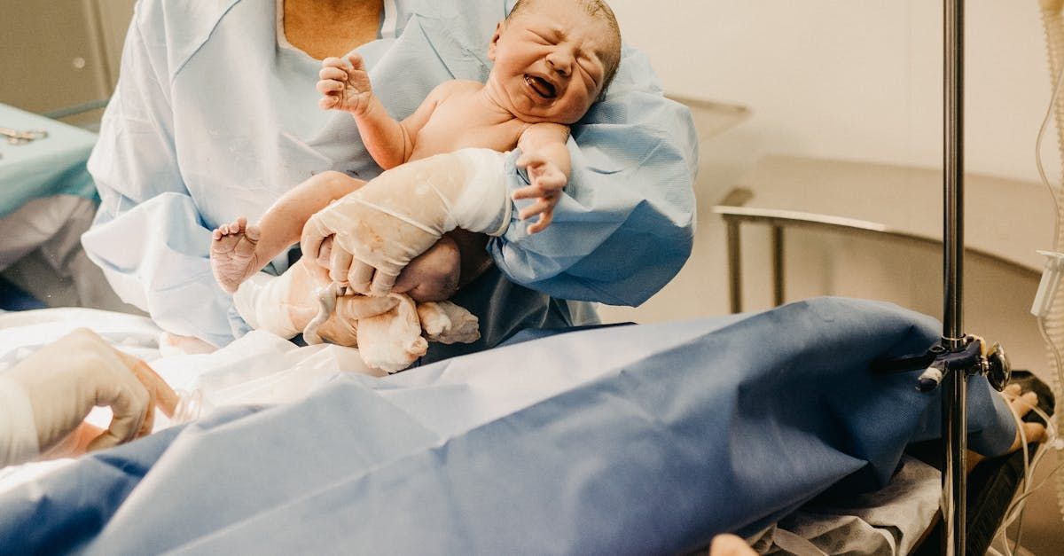 A woman is holding a newborn baby in a hospital bed.