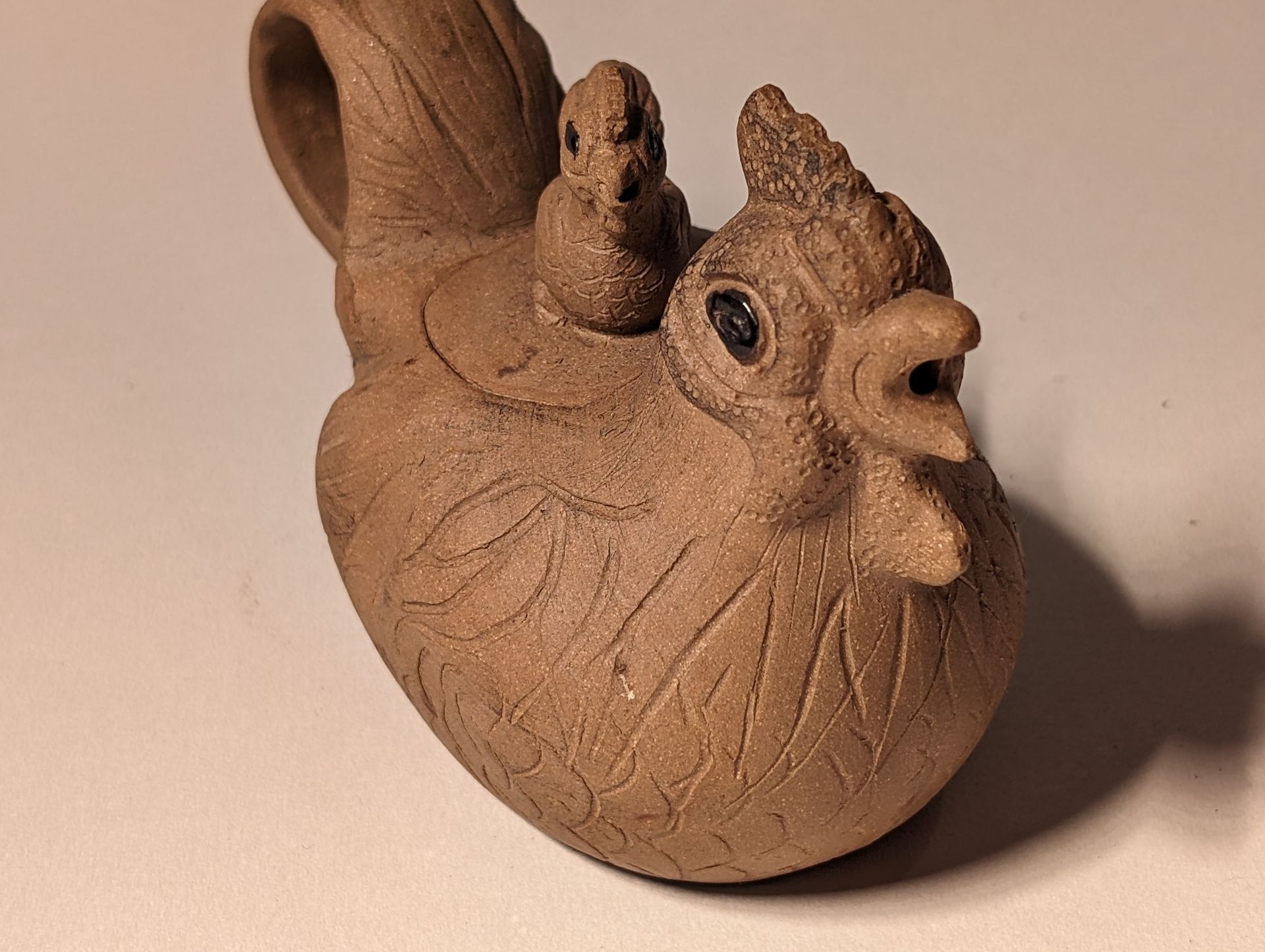 A statue of a chicken with two chicks on its back