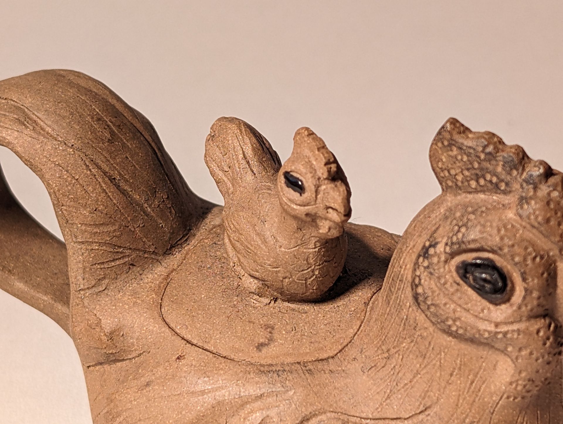 A statue of a chicken with a mouse on its back