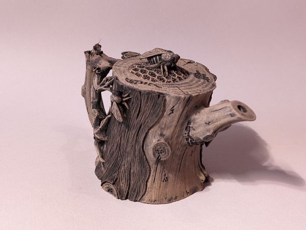 Small sculpted wooden stump with carved bird and tree branch details, on a plain light background