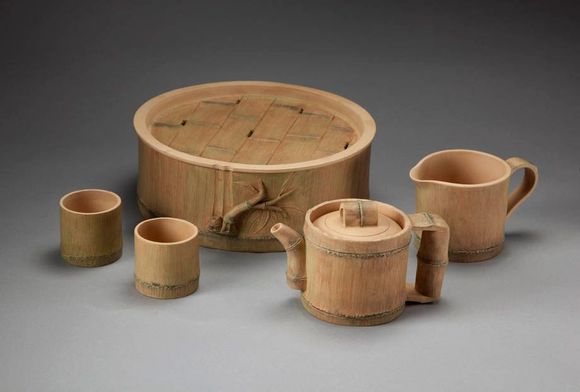 Wooden cups, mugs, and a lidded bowl arranged on a gray surface.