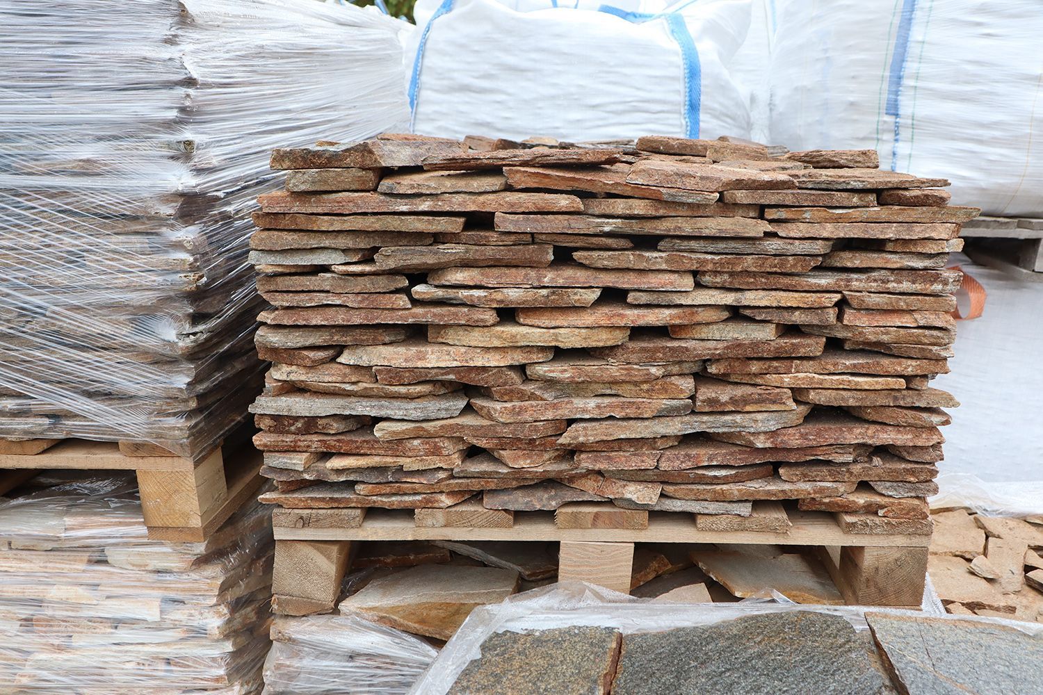 Stack of natural stone pavers arranged on a pallet at an outdoor landscaping supply yard. Stack of natural stone pavers arranged on a pallet at an outdoor landscaping supply yard.