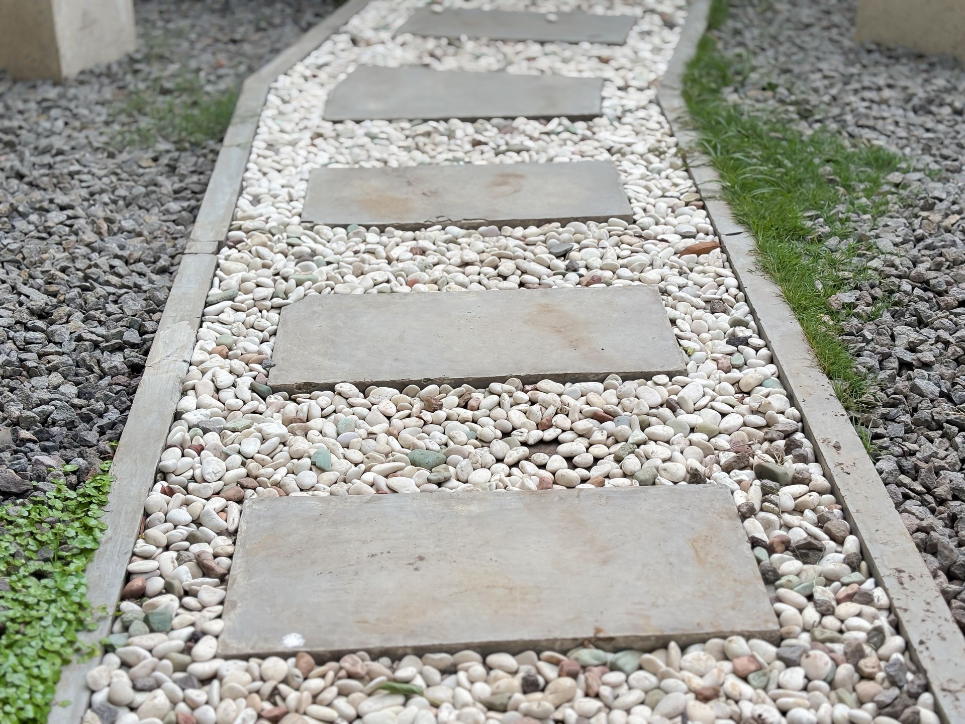 Accent stone walkway framed by gravel, bordered with clean concrete edging