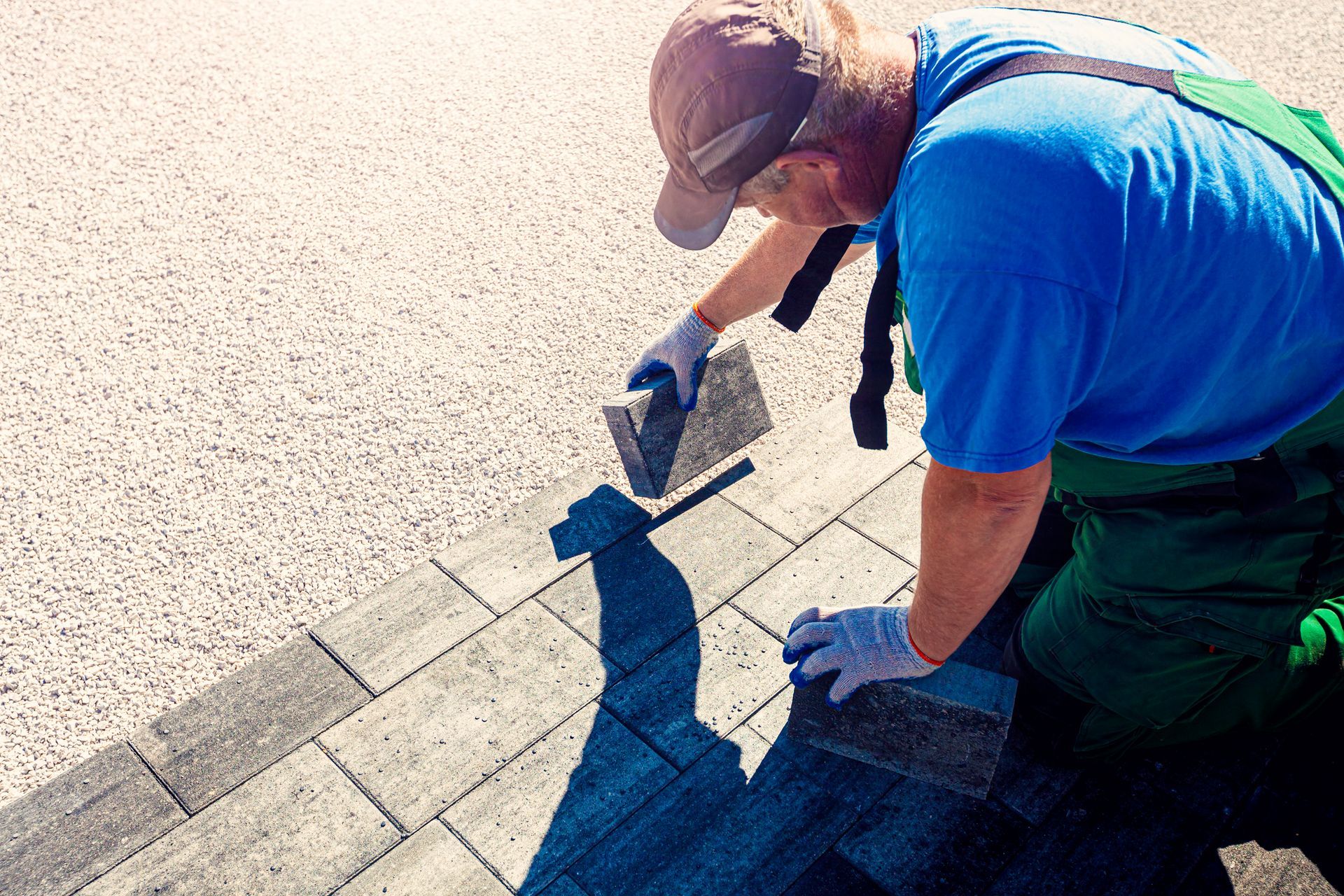 Worker laying paving stones by hand from a trusted landscaping paver supplier on site.