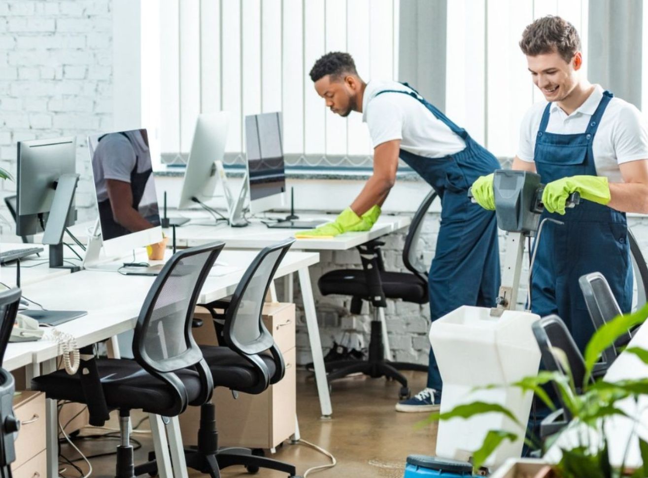 Due uomini stanno pulendo un ufficio con un aspirapolvere.