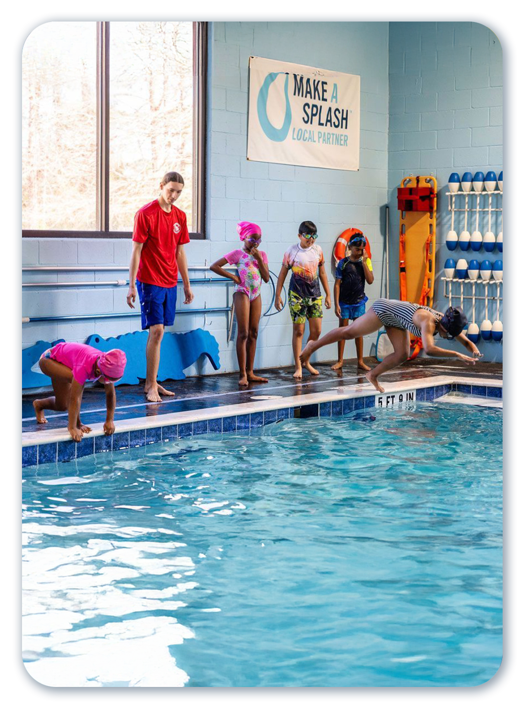 Children at a swimming pool, learning to dive under the supervision of a lifeguard.