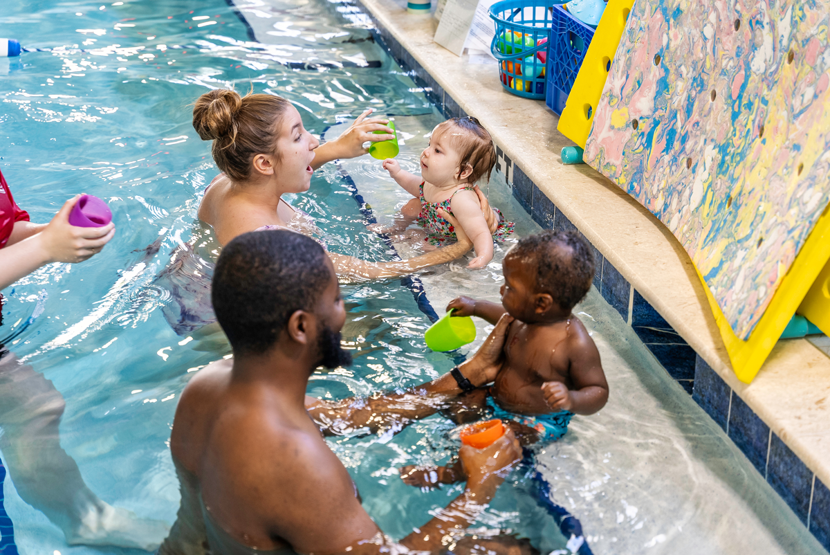 Adults and children in a swimming pool, playing with toys. Bright colors, happy expressions.