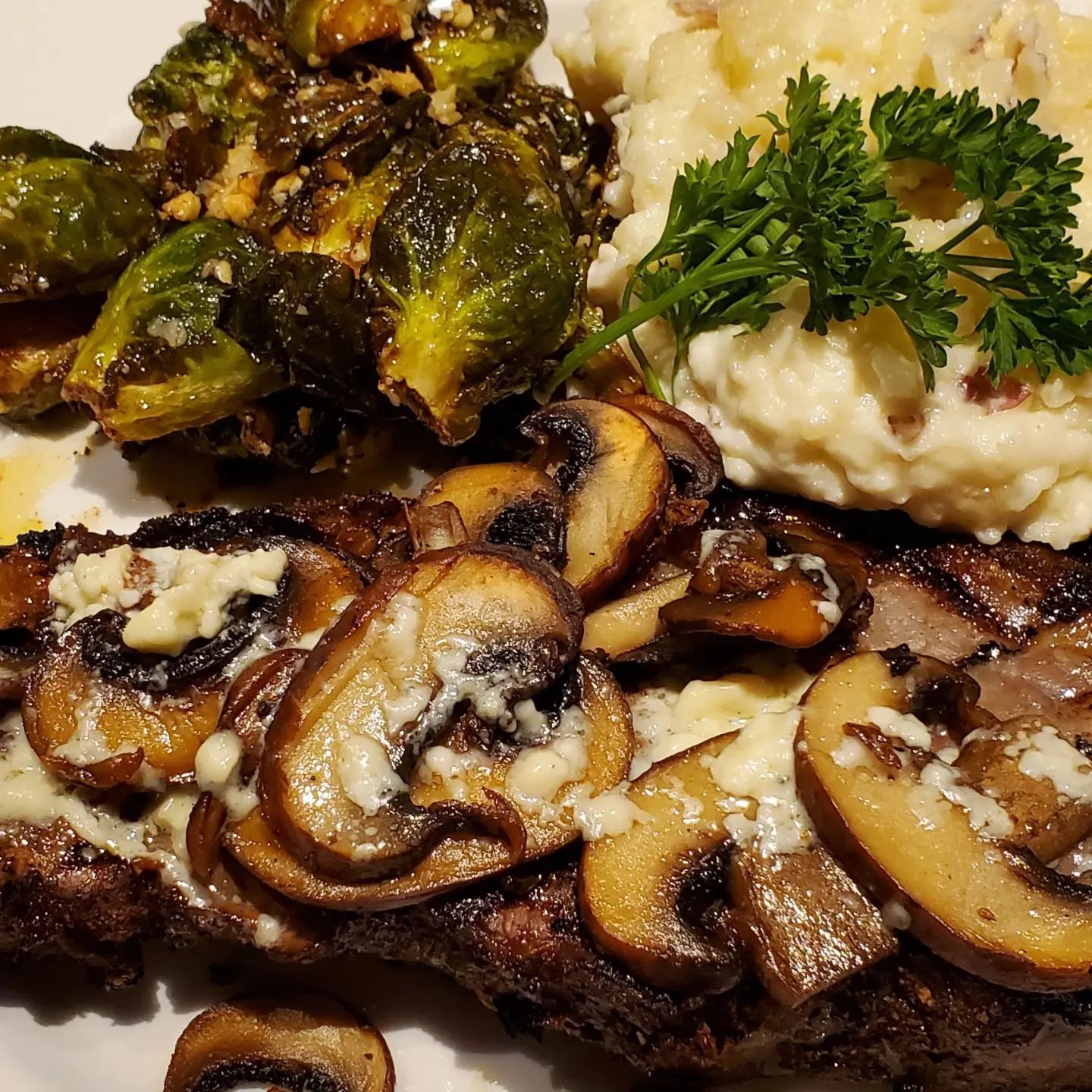Steak with mushrooms and blue cheese, mashed potatoes, and roasted Brussels sprouts.