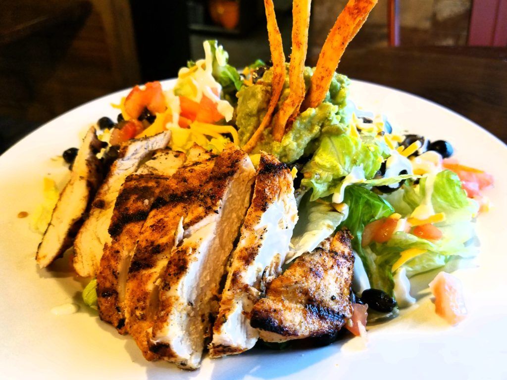 Grilled chicken salad with black beans, guacamole, and tortilla strips.