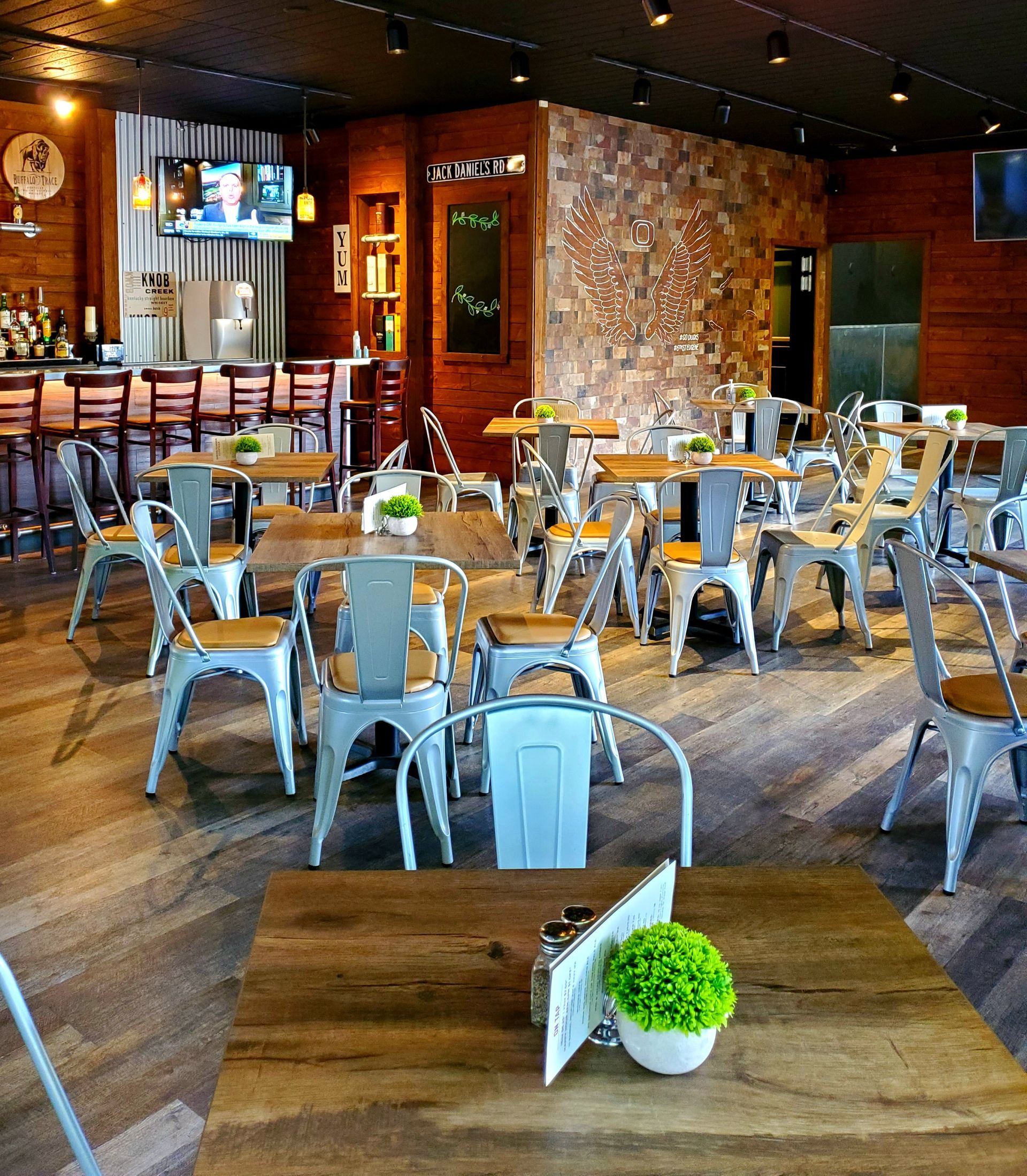 Restaurant interior with tables, chairs, bar area, and decorative stone wall.