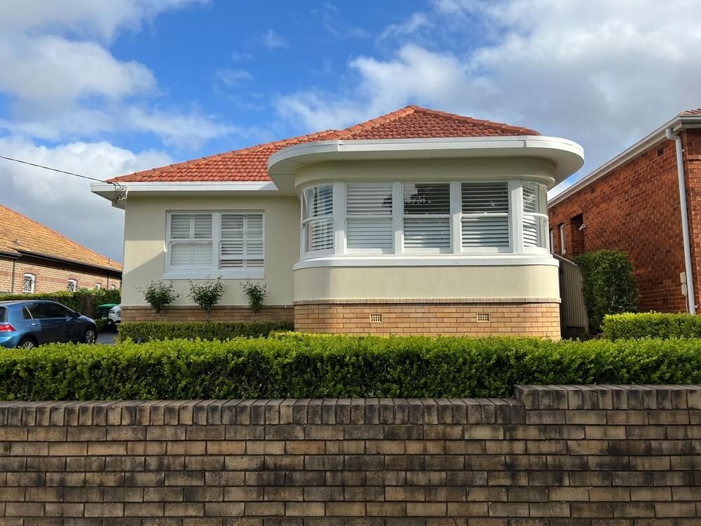 A White House with A Red Roof Is Surrounded by A Brick Wall and Bushes — Marks Financial Group in  Toowoomba City, QLD