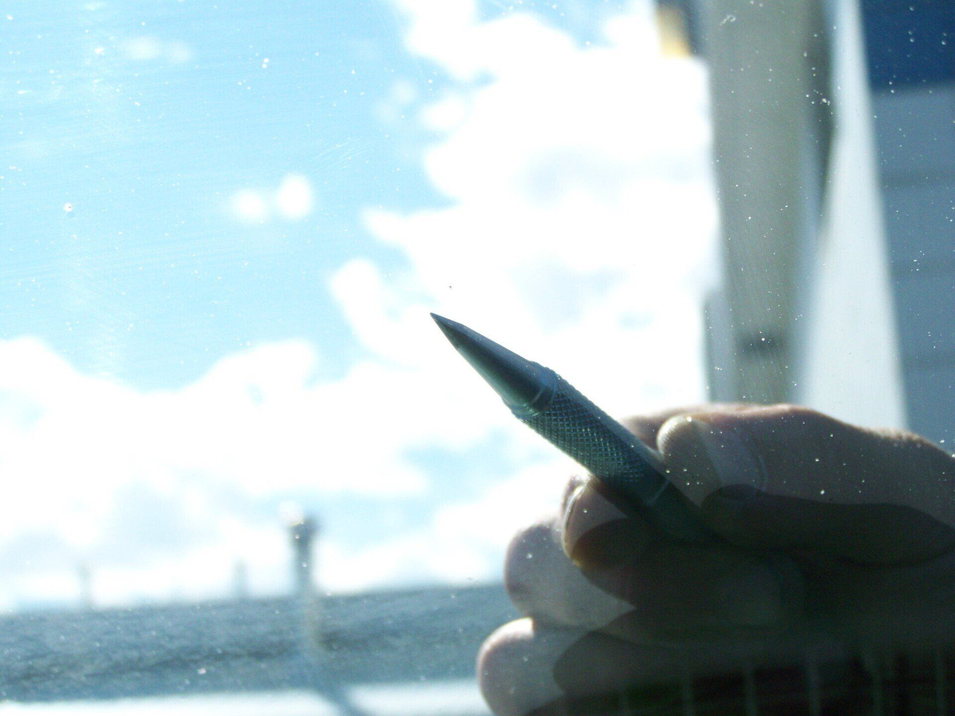 A person holding a pen in front of a window