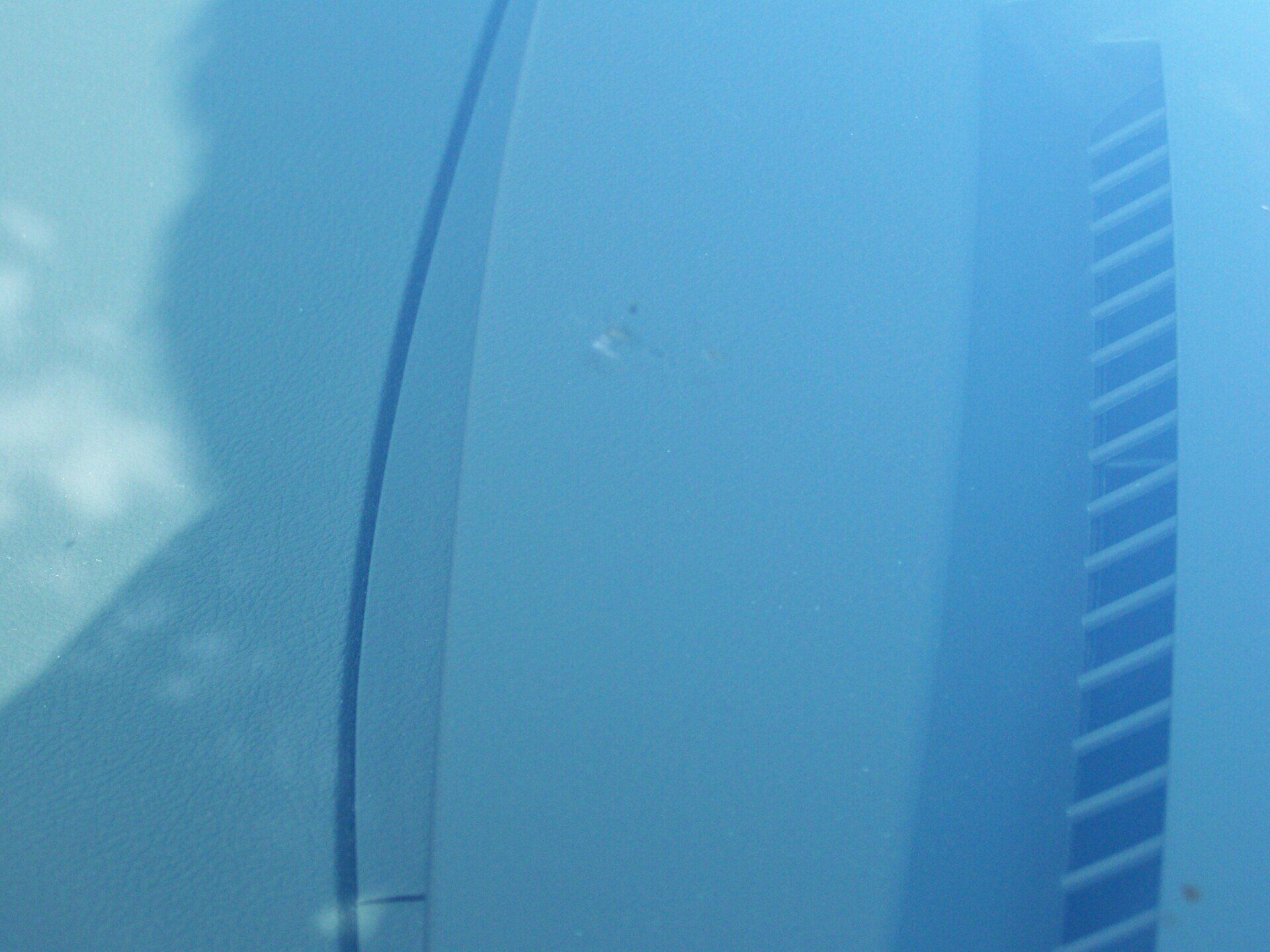 A close up of a blue car windshield with a reflection of a building in it.