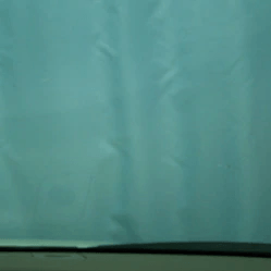 A close up of a blue shower curtain on a window.