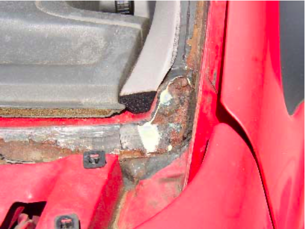 A close up of a red car with rust on it