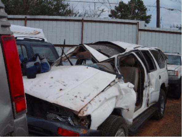 A wrecked white suv is parked in a lot
