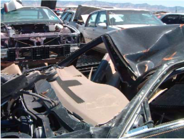 A wrecked car sits in a pile of other cars