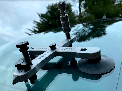 A tool is sitting on top of a car windshield