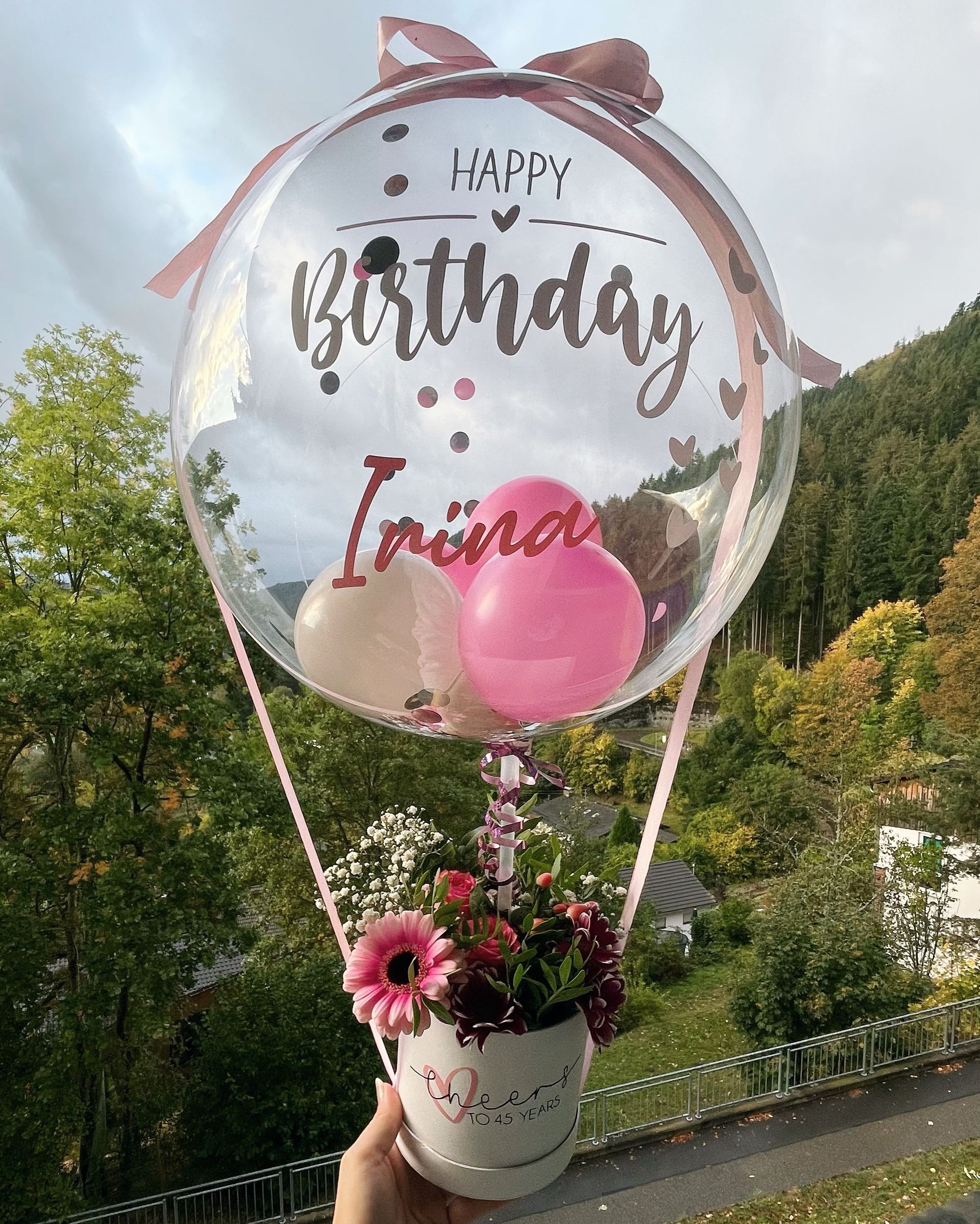 Eine Person hält einen Heißluftballon mit Blumen darin.