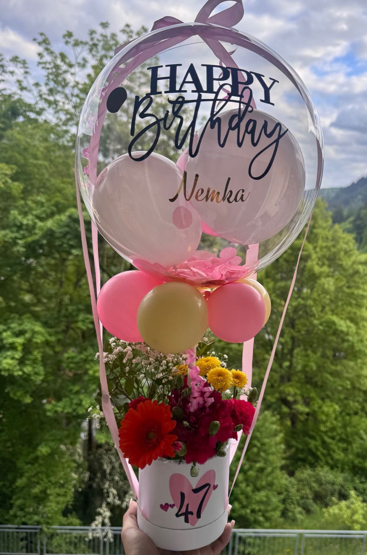 Geburtstagsballonstrauß mit Blumen: durchsichtiger Ballon, Aufschrift „Happy Birthday Nemka“