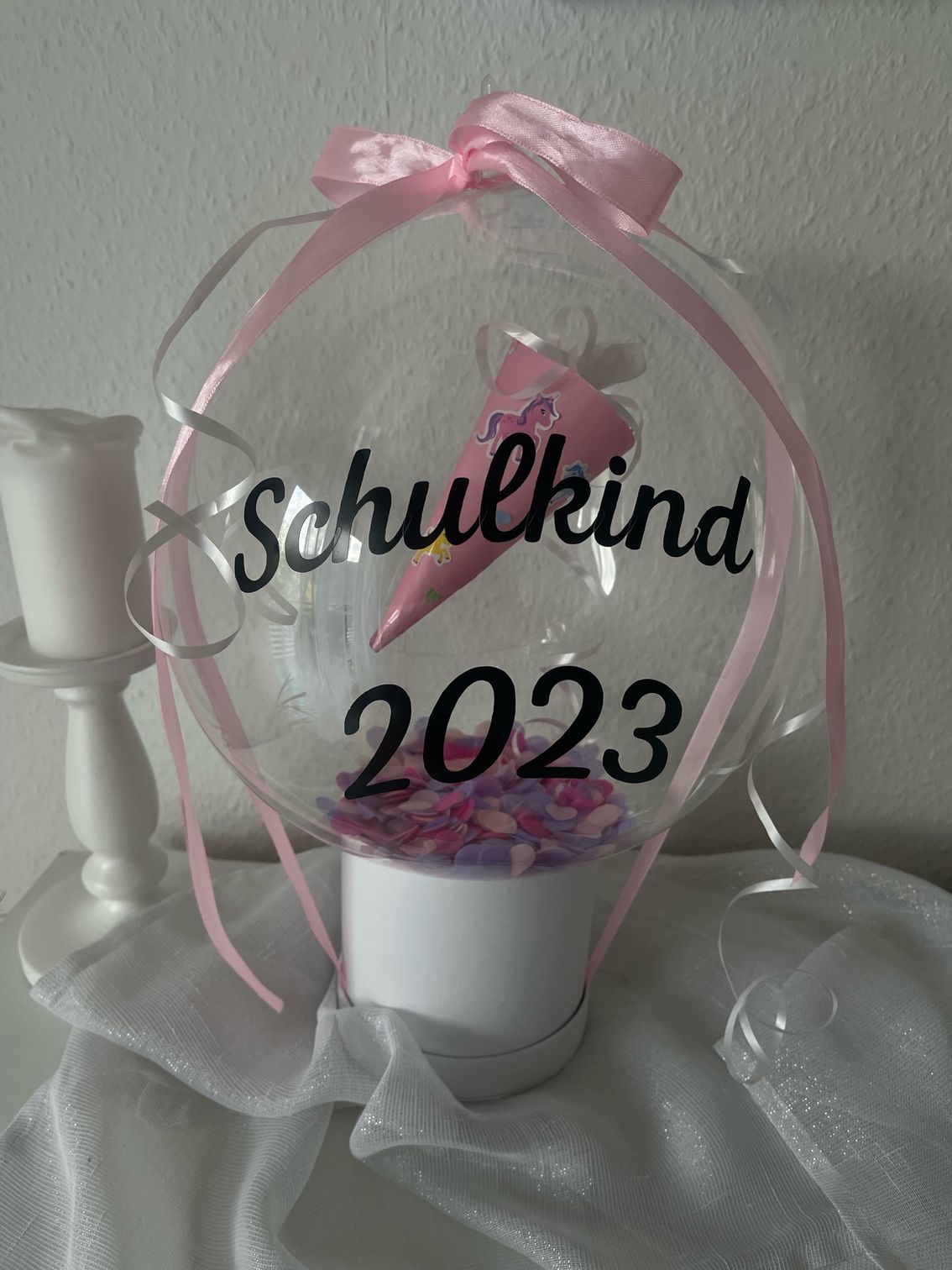 Auf einem Tisch steht ein durchsichtiger Ballon mit der Aufschrift „Schulkind 2023“.