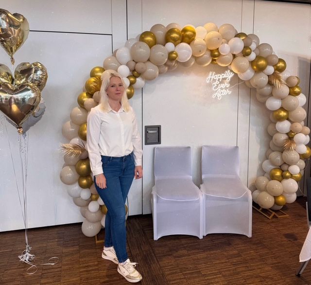 Eine Frau hält einen schwarzen Luftballon mit der Aufschrift „Es ist ein Mädchen!“. 