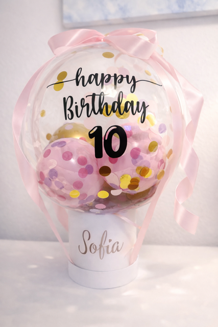 In einem durchsichtigen Ballon hängt ein rotes Hemd mit einem Teddybären darauf.