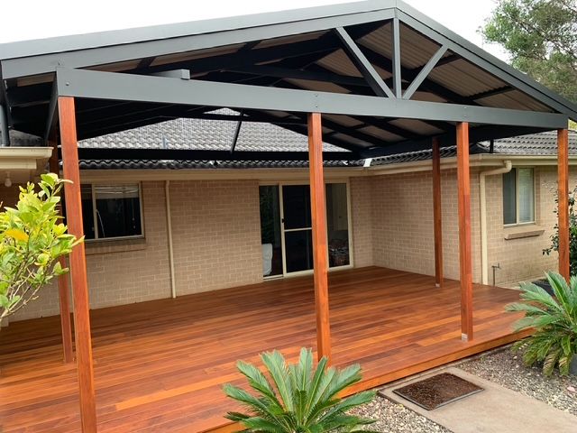 A wooden pergola with a clear roof is sitting next to a pool.