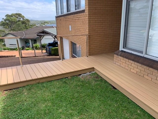 A wooden deck is sitting in front of a brick house.