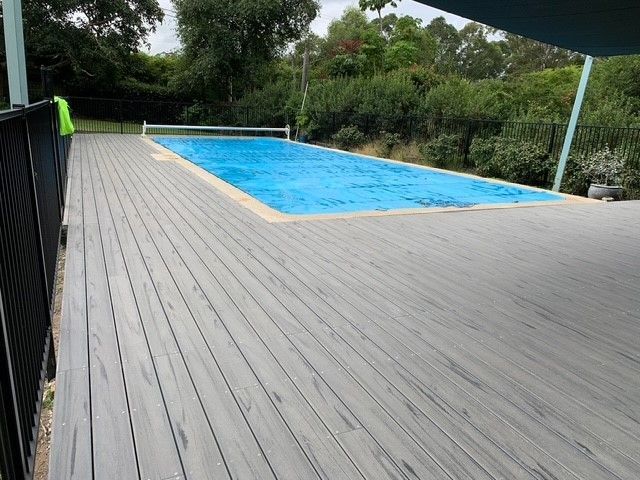 A large swimming pool is surrounded by a wooden deck.