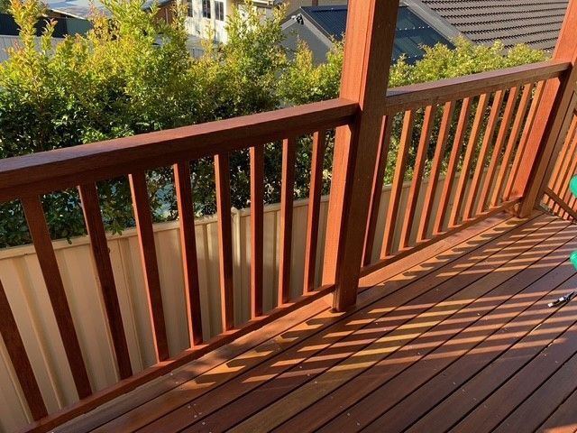 A wooden deck with a railing and a chair on it.