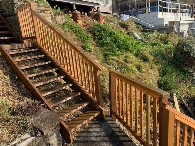 A set of wooden stairs leading up to a house on a hill.