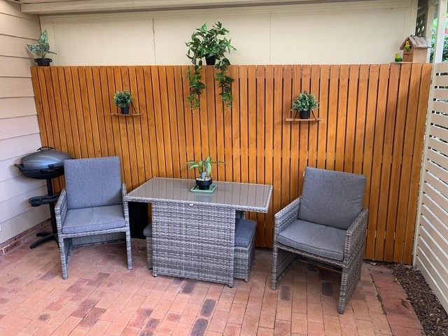 A patio with a table and chairs in front of a wooden fence.
