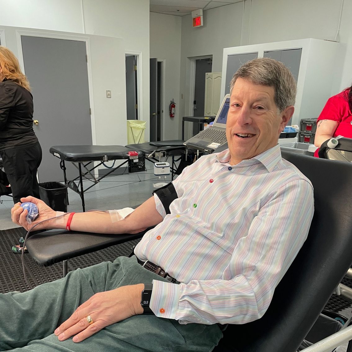 Joe Pereles is sitting in a chair donating blood.