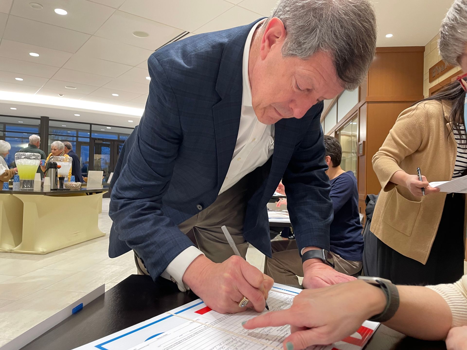 Joe Pereles signing a document at an event