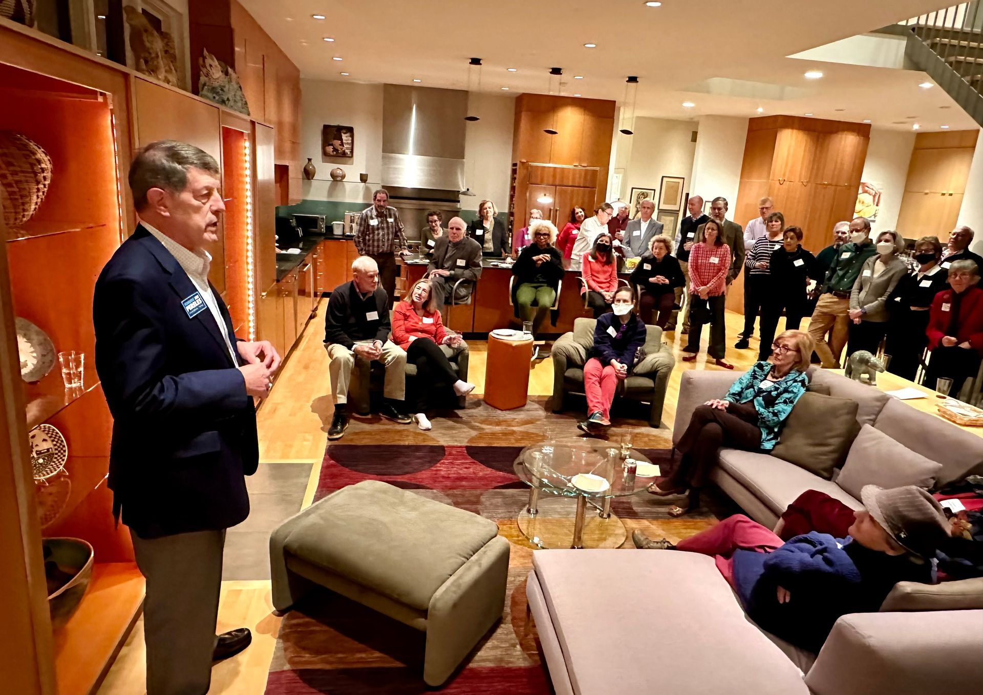 Joe Pereles is standing in front of a group of people in a living room.