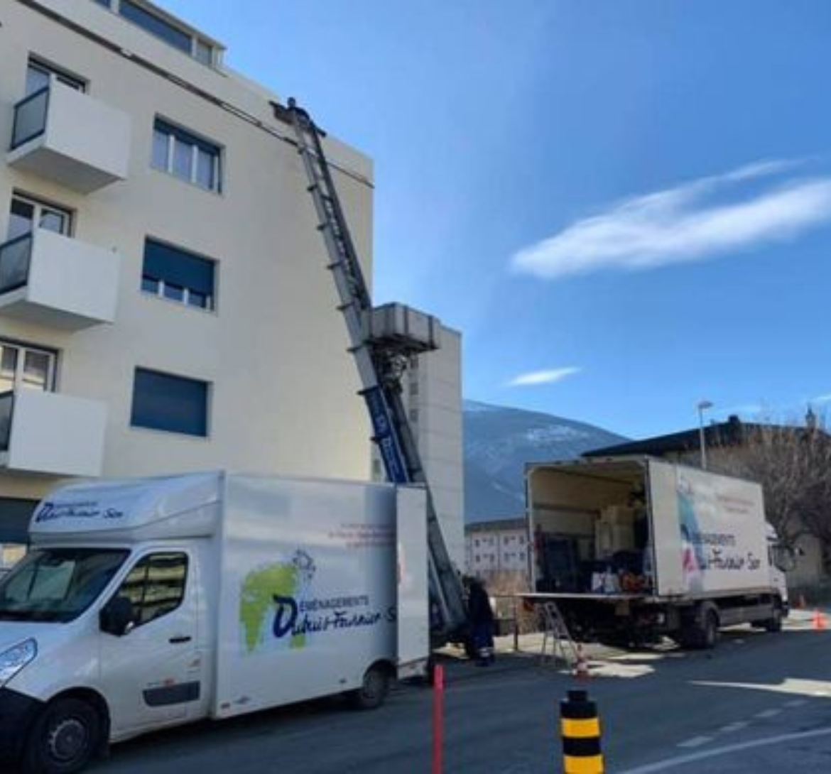 Deux camions de déménagement sont garés devant un immeuble