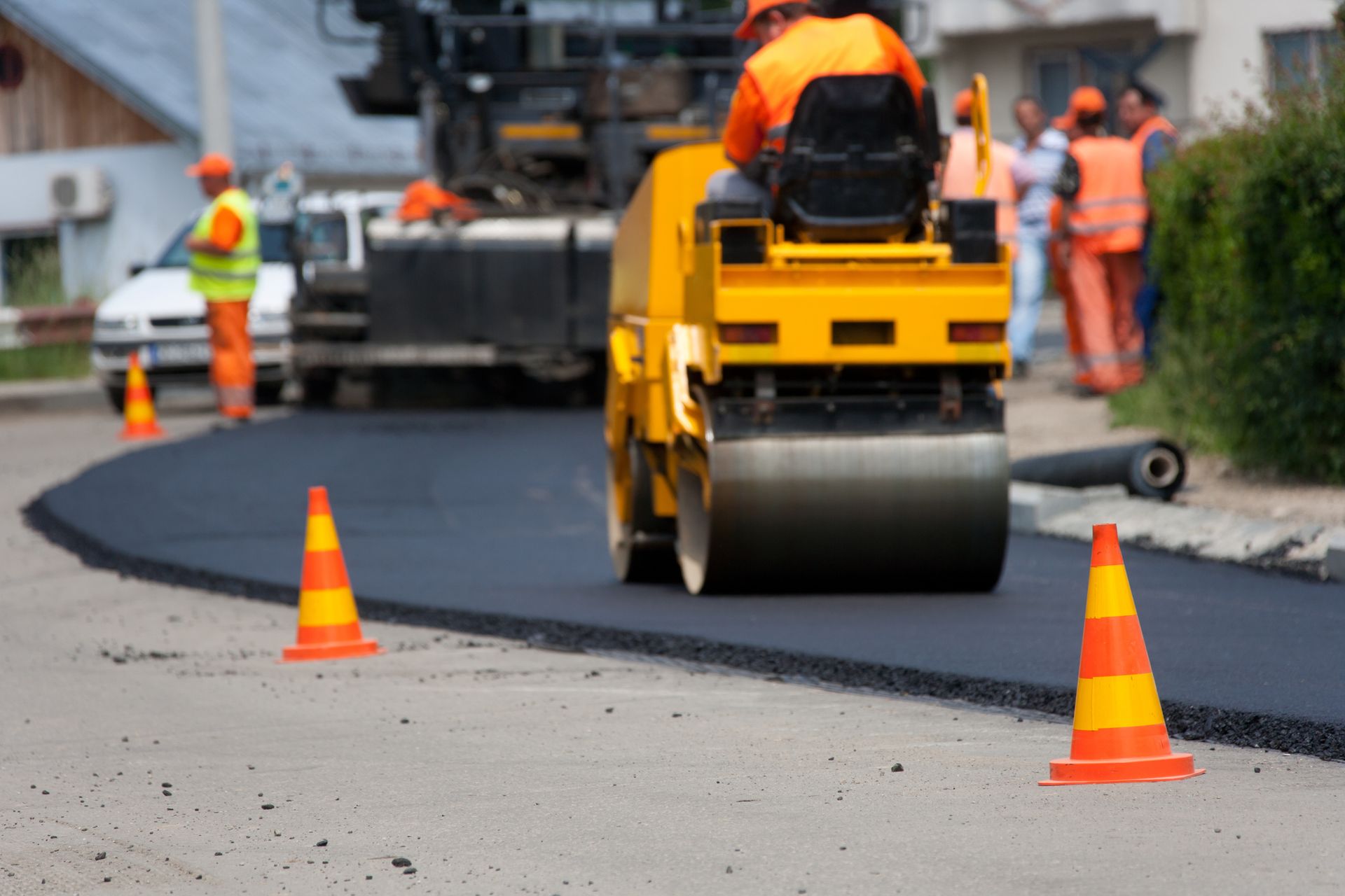 Asphalt paving contractor using a spreader to lay the first layer of asphalt on a city street.