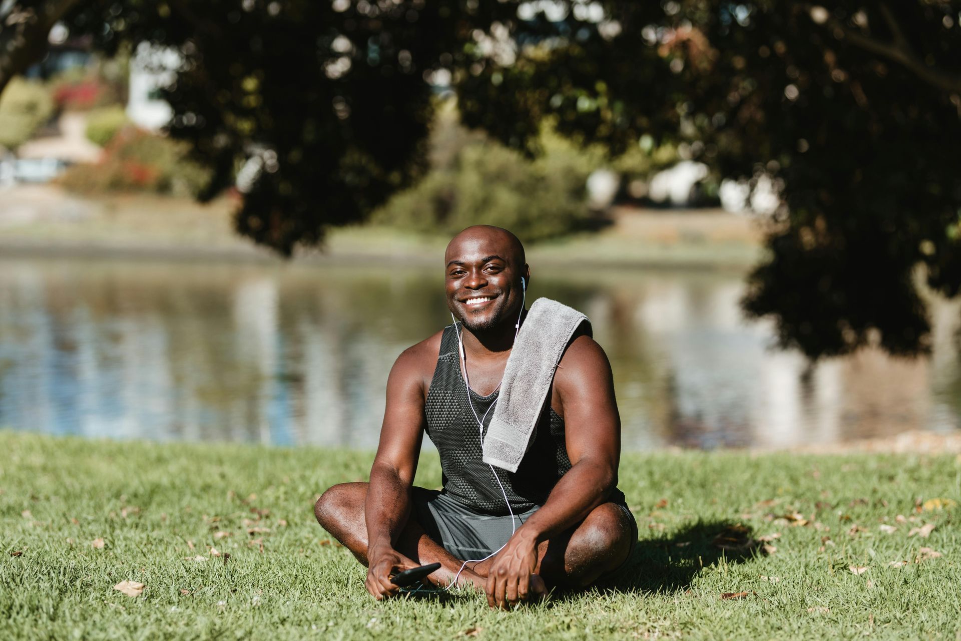 A black man sitting on the grass in a park after a workout session