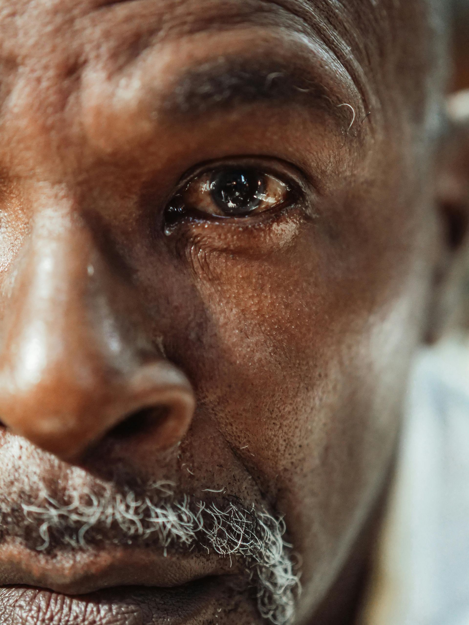 An elderly black man looking sad due to pain