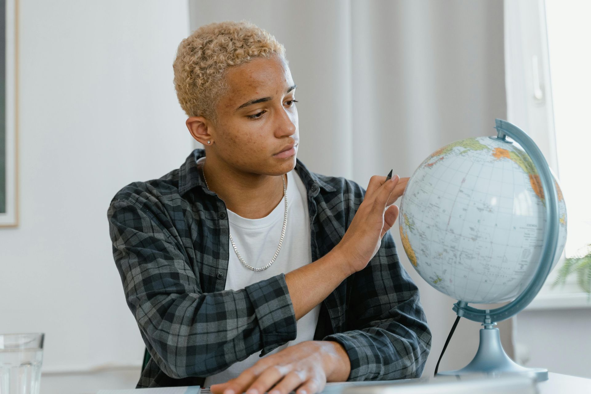 A young man touches a globe, symbolizing the collective global effort and responsibility to UHC