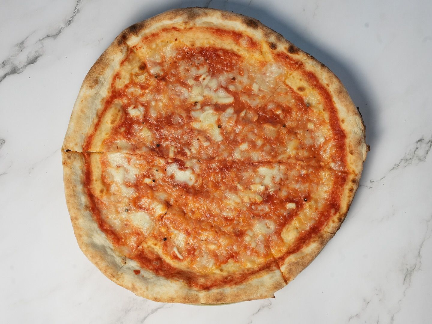 Pizza al formaggio su un piano di marmo; salsa di pomodoro e formaggio fuso.