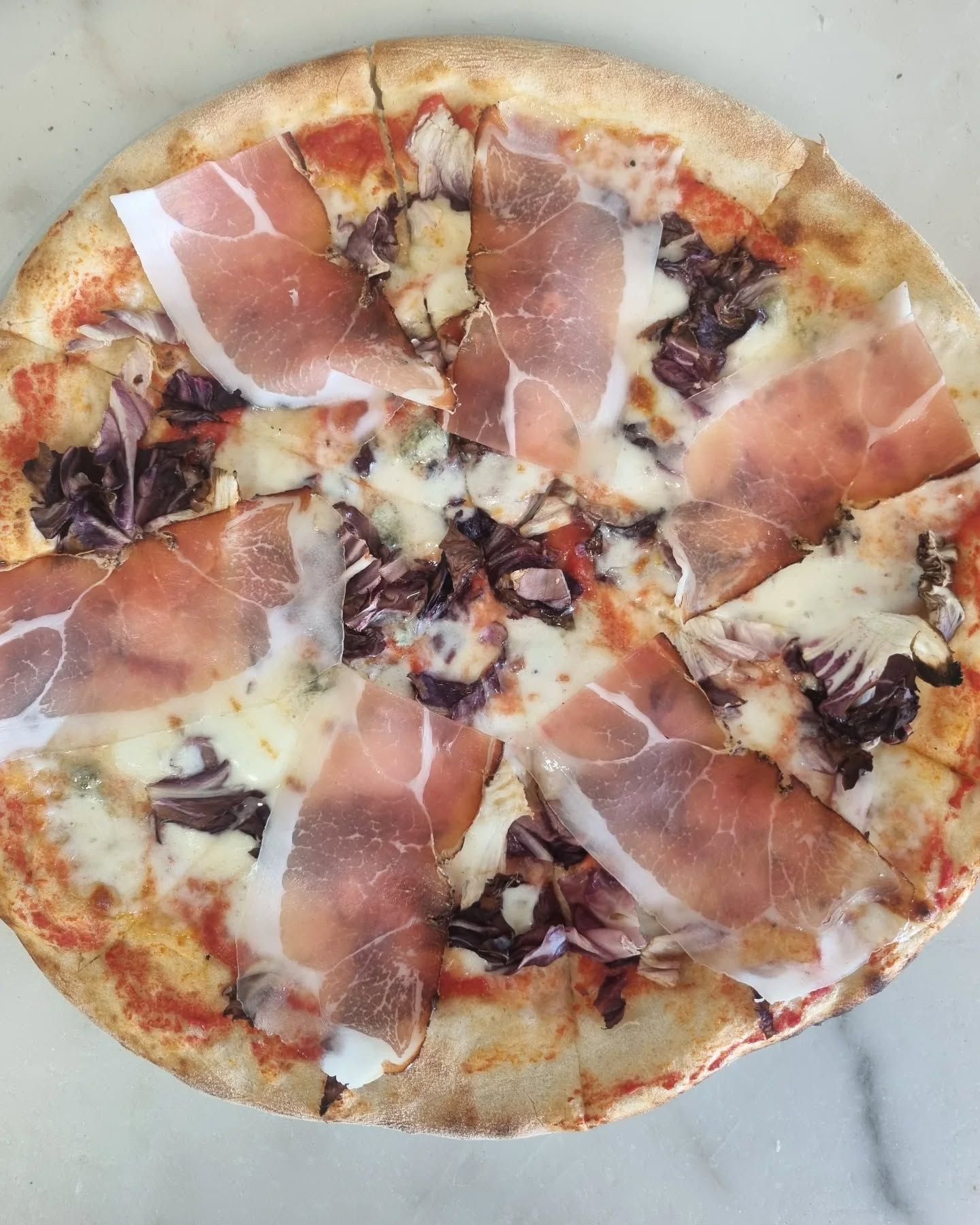Pizza con prosciutto, formaggio e radicchio.