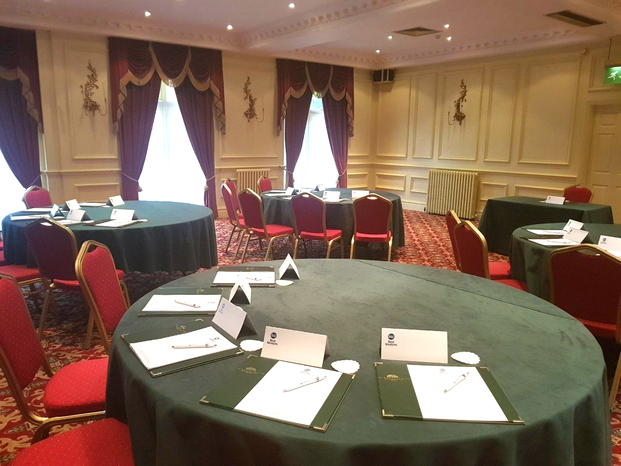 A conference room with round tables and red chairs