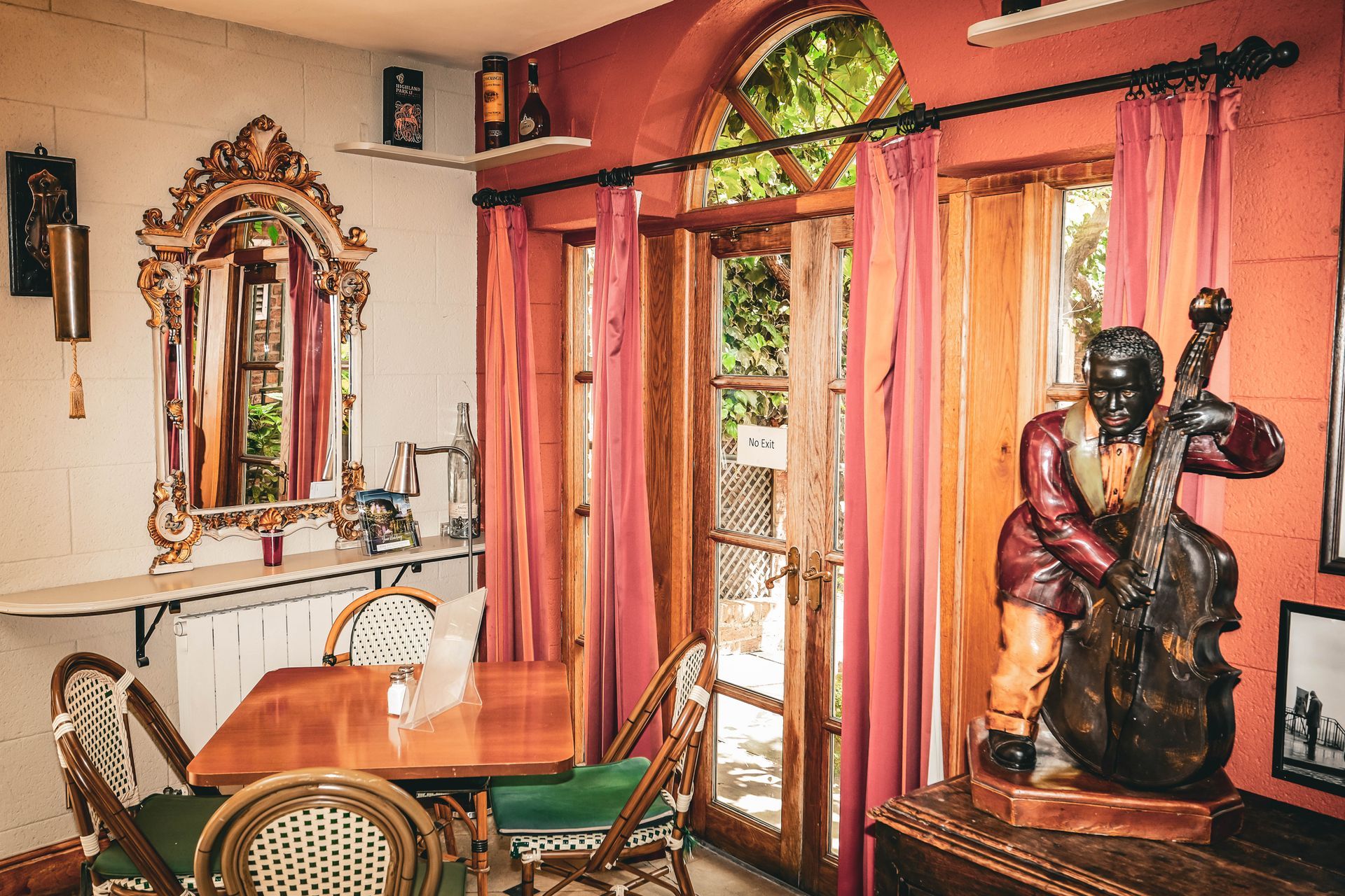 A room with a table and chairs and a statue of a man playing a double bass.